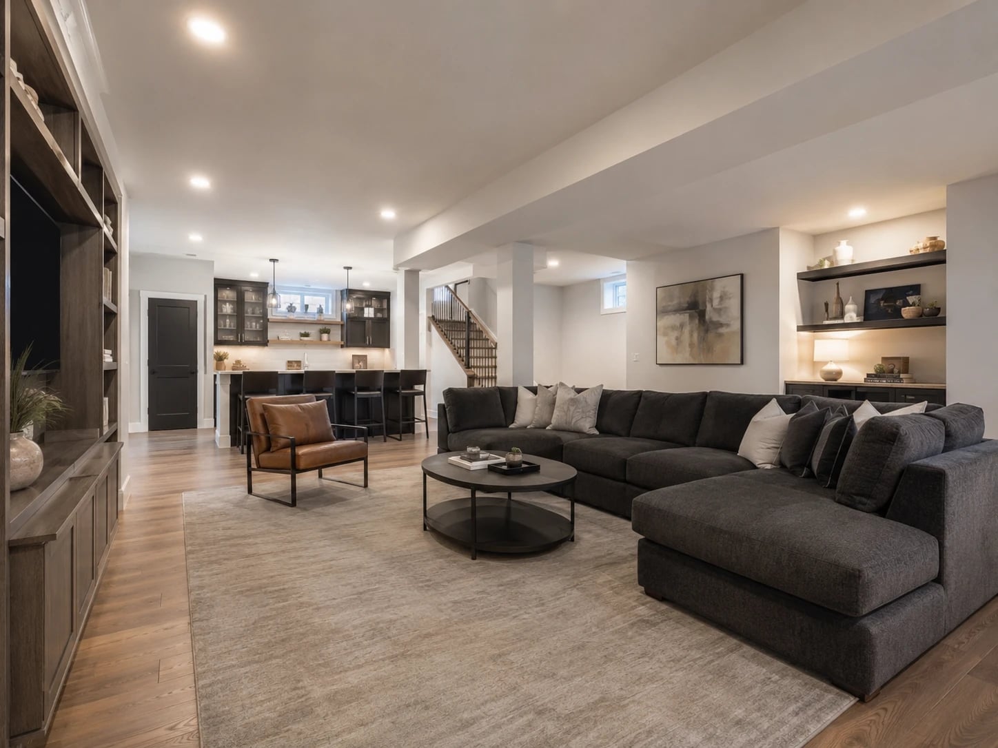 Finished residential basement with open living area, built-in bar and modern lighting.