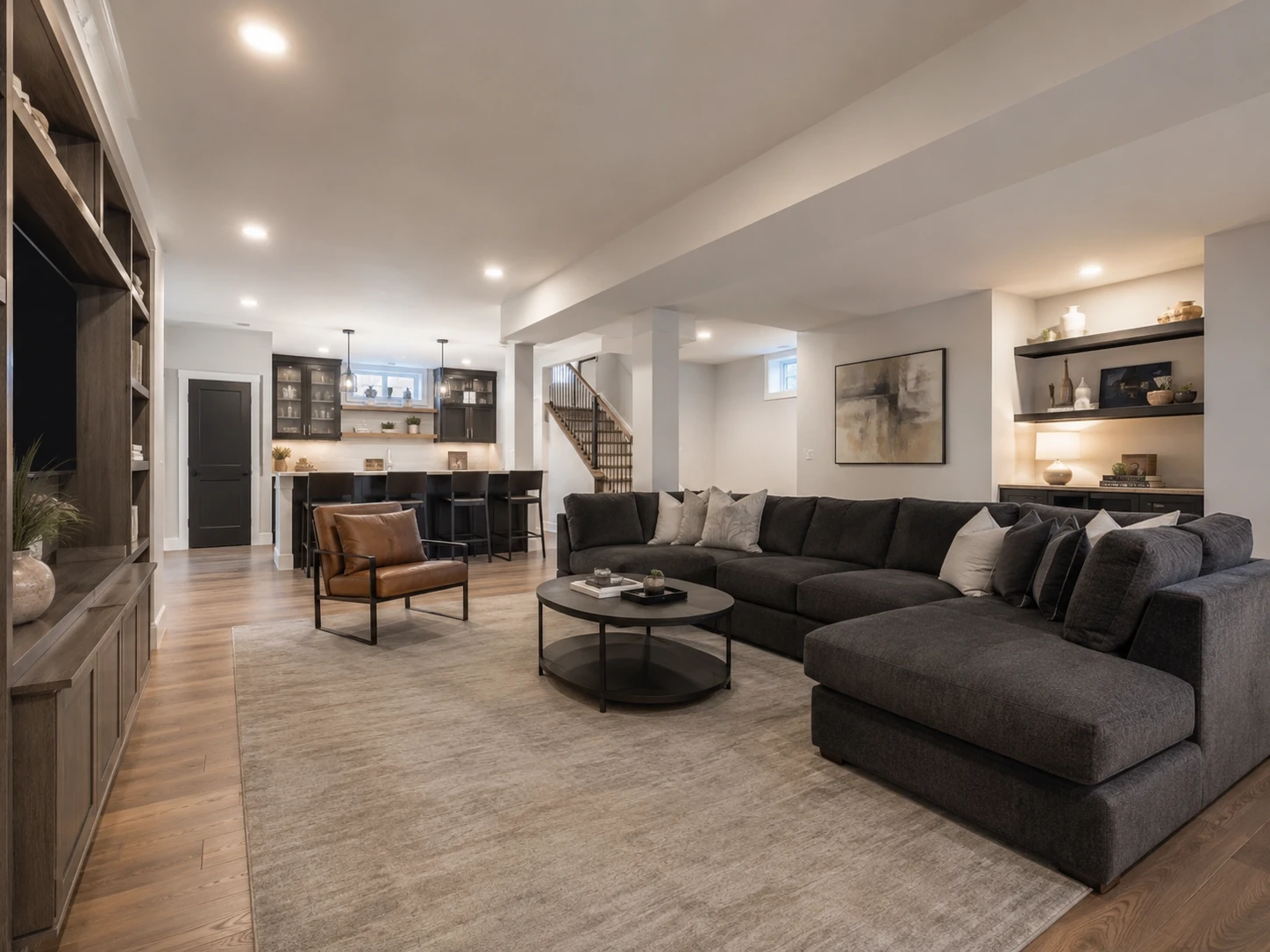 Finished residential basement with open living area, built-in bar and modern lighting.