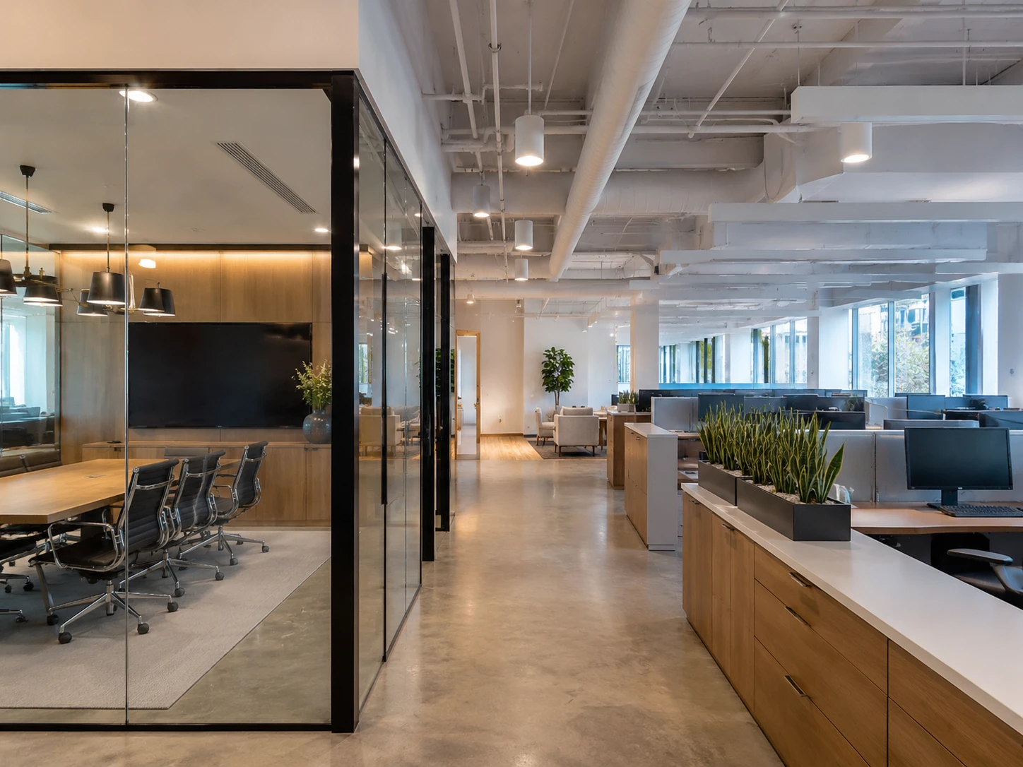 Renovated open-plan office with glass conference room, wood millwork and modern workstations.