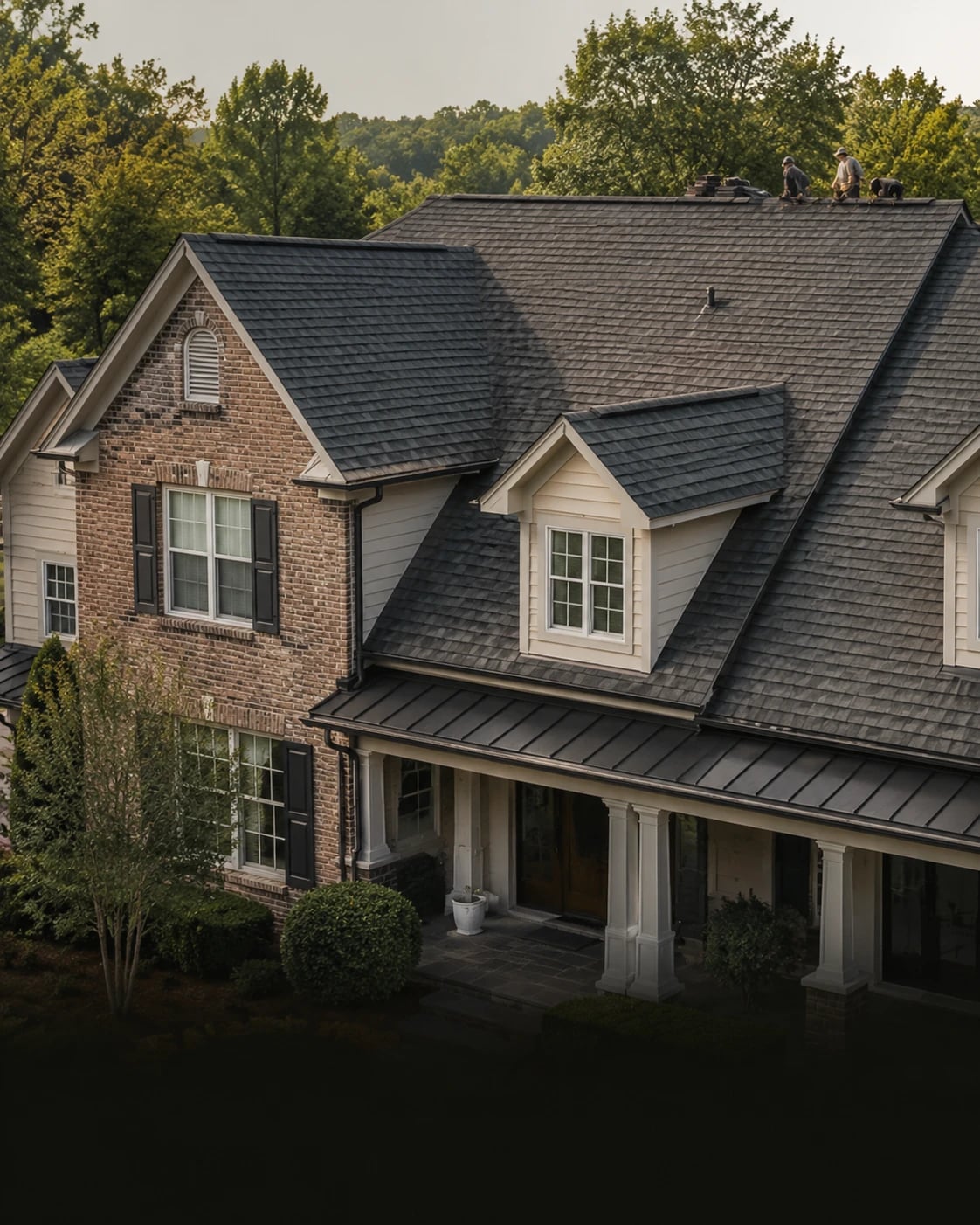 Two-story brick residence with a new dark asphalt shingle roof and standing-seam porch roof.